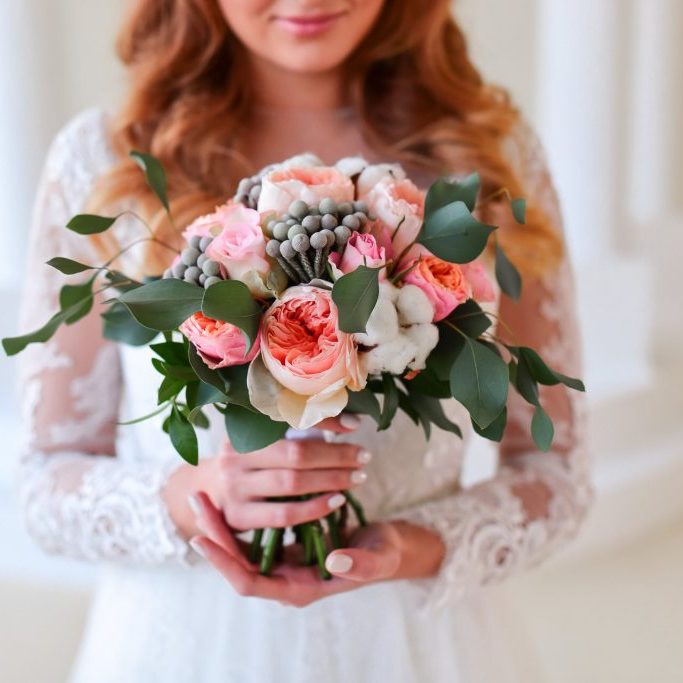 Young bride holds pink wedding bouquet